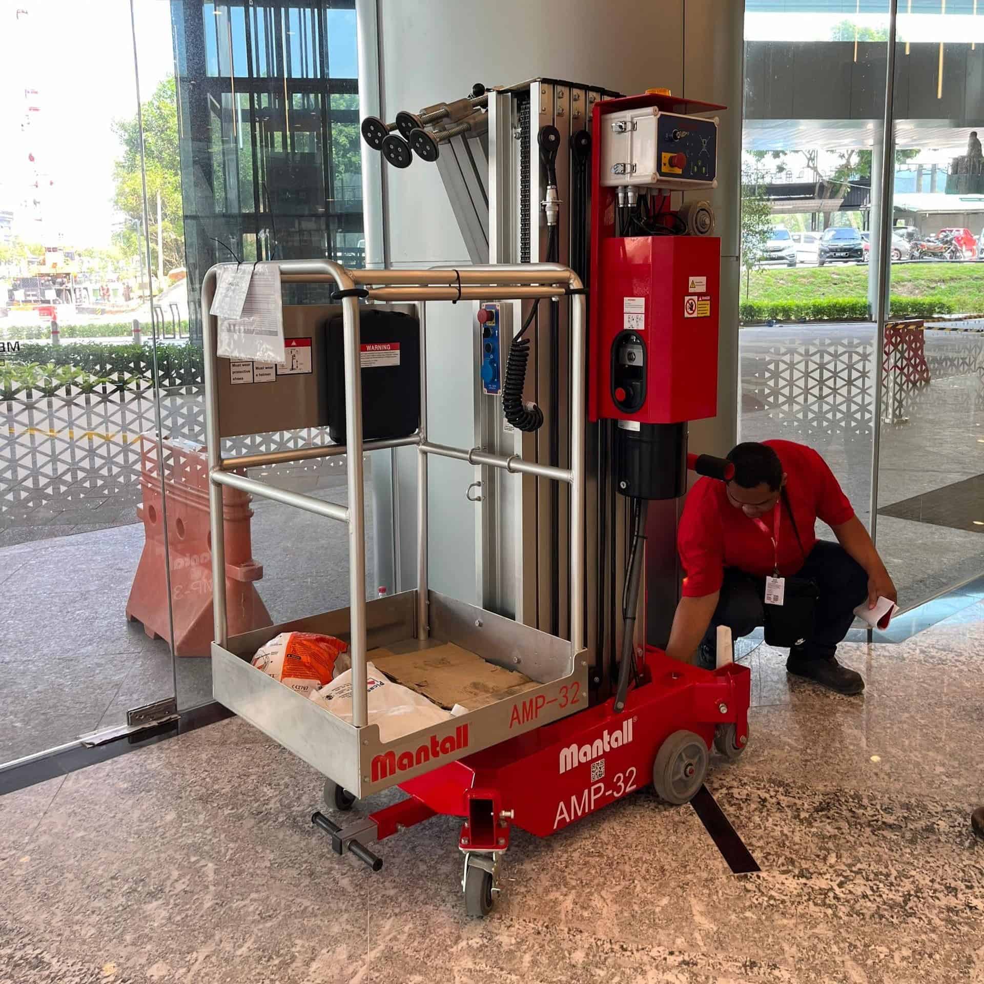 Red Mantall vertical lift MEWP for indoor building maintenance.